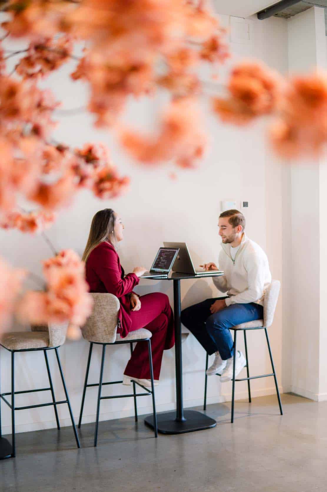 Online marketeers overleggen aan hoge statafel. In de voorgrond zie je een wazige roze boom.