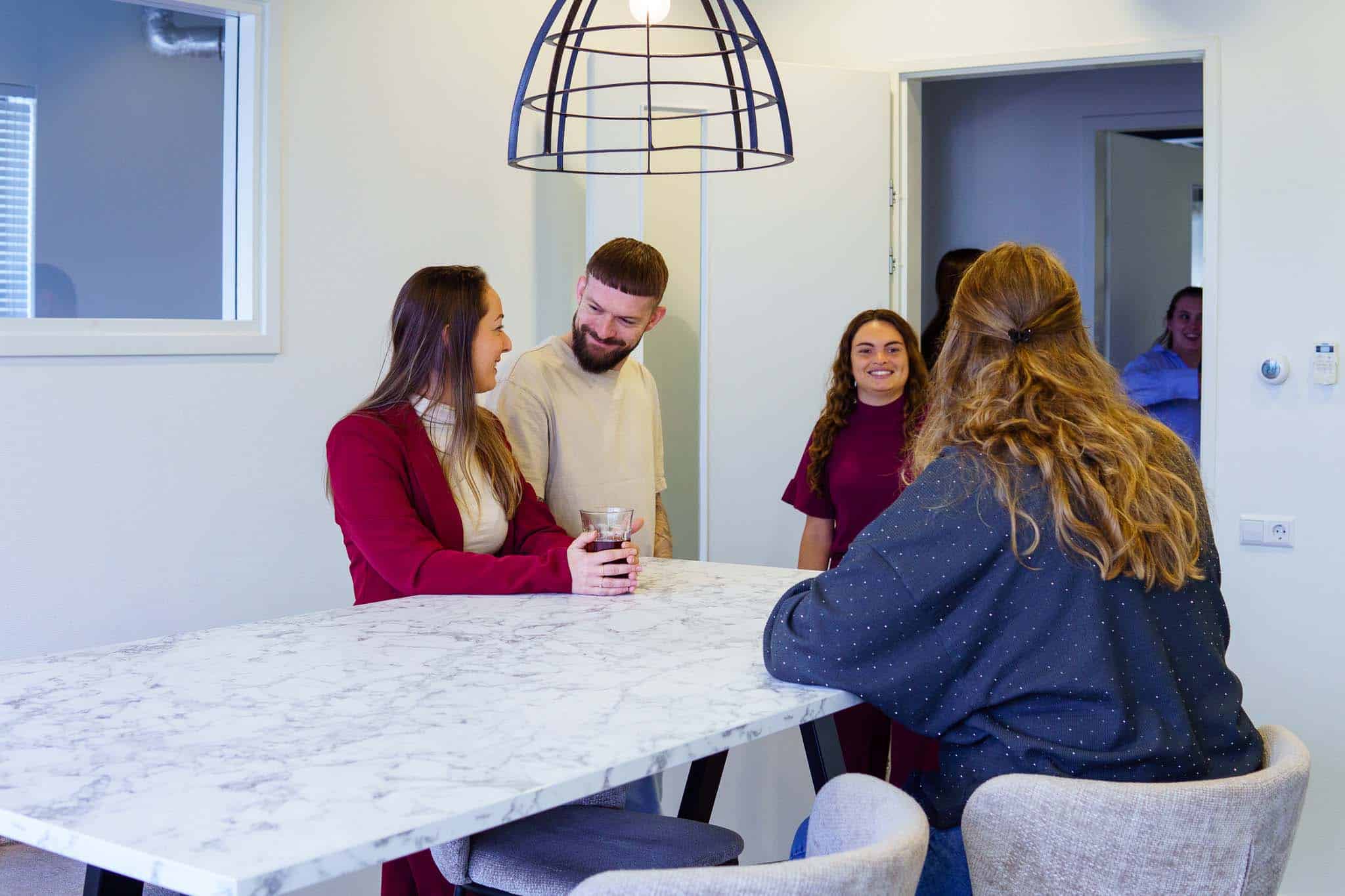 Collega's van BURO210 in een informele setting bij elkaar om een tafel