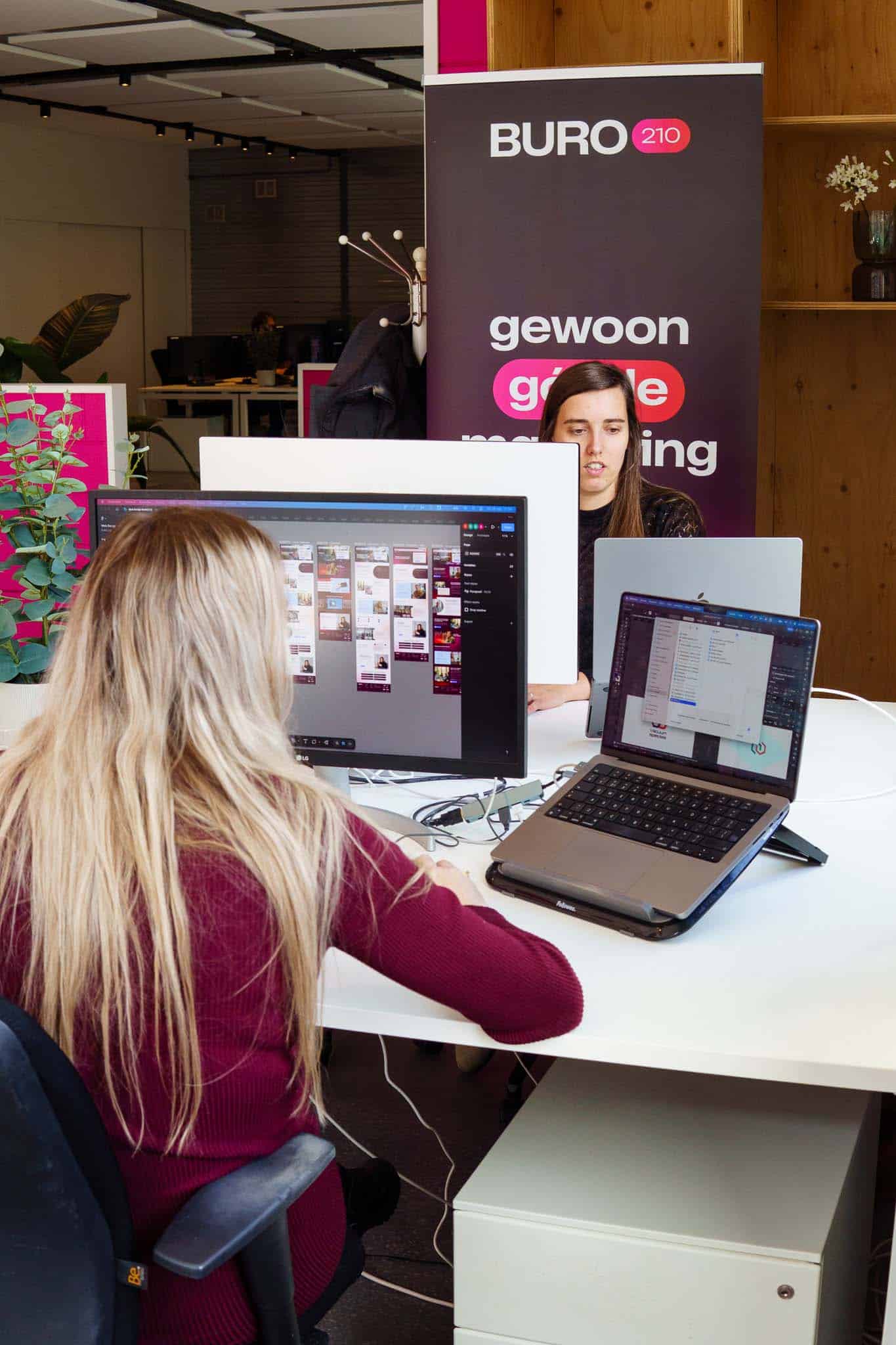 BURO210 Fullservice Marketingbureau Jonge vrouwen werken samen in een modern kantoor aan designprojecten. Computers, laptops en creatieve software worden gebruikt bij Bureau 210 om websites te ontwerpen.