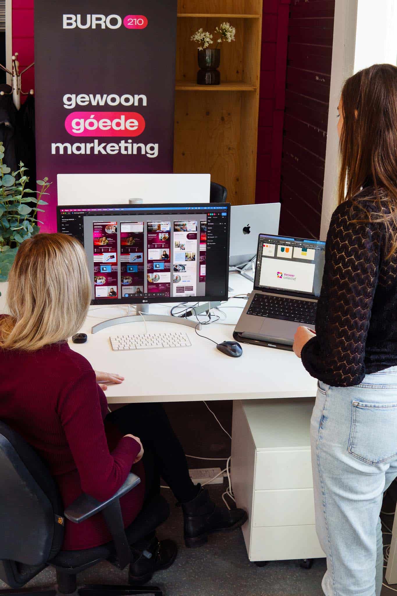 BURO210 Fullservice Marketingbureau Twee collega's van BURO 210 werken samen aan een webdesign project op kantoor, met een focus op 'gewoon goede marketing' en visuele aantrekkingskracht.