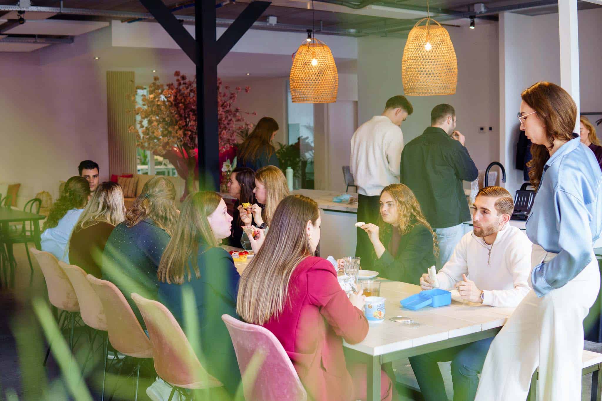 BURO210 Fullservice Marketingbureau Groep jonge professionals geniet van een gezellige lunchpauze in een moderne kantooromgeving, met focus op team building en ontspanning tijdens het werk.