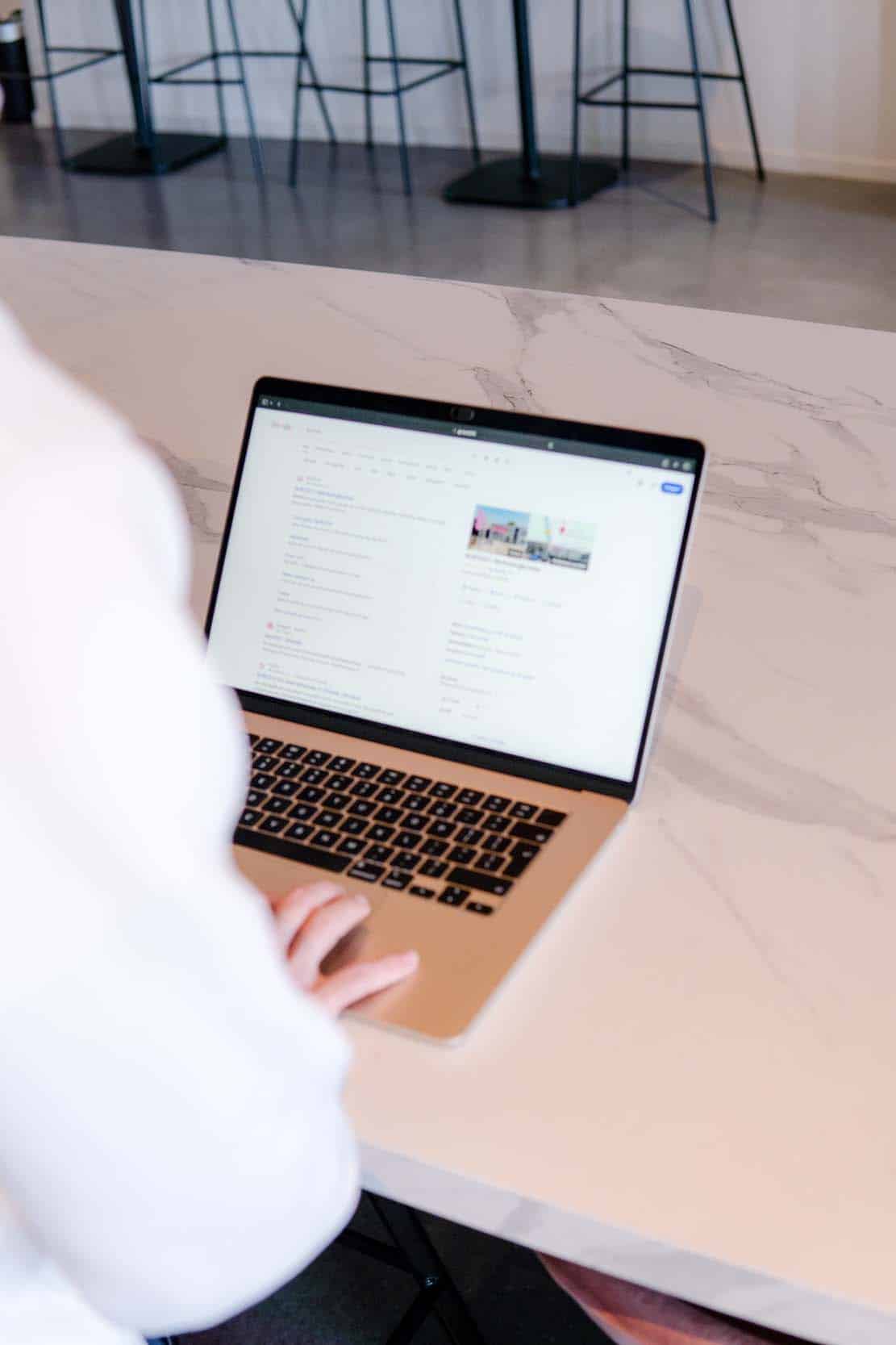 BURO210 Fullservice Marketingbureau Persoon gebruikt een laptop op een marmeren aanrecht om online te zoeken. Focus ligt op de technologie en het gebruik van internet in huis.