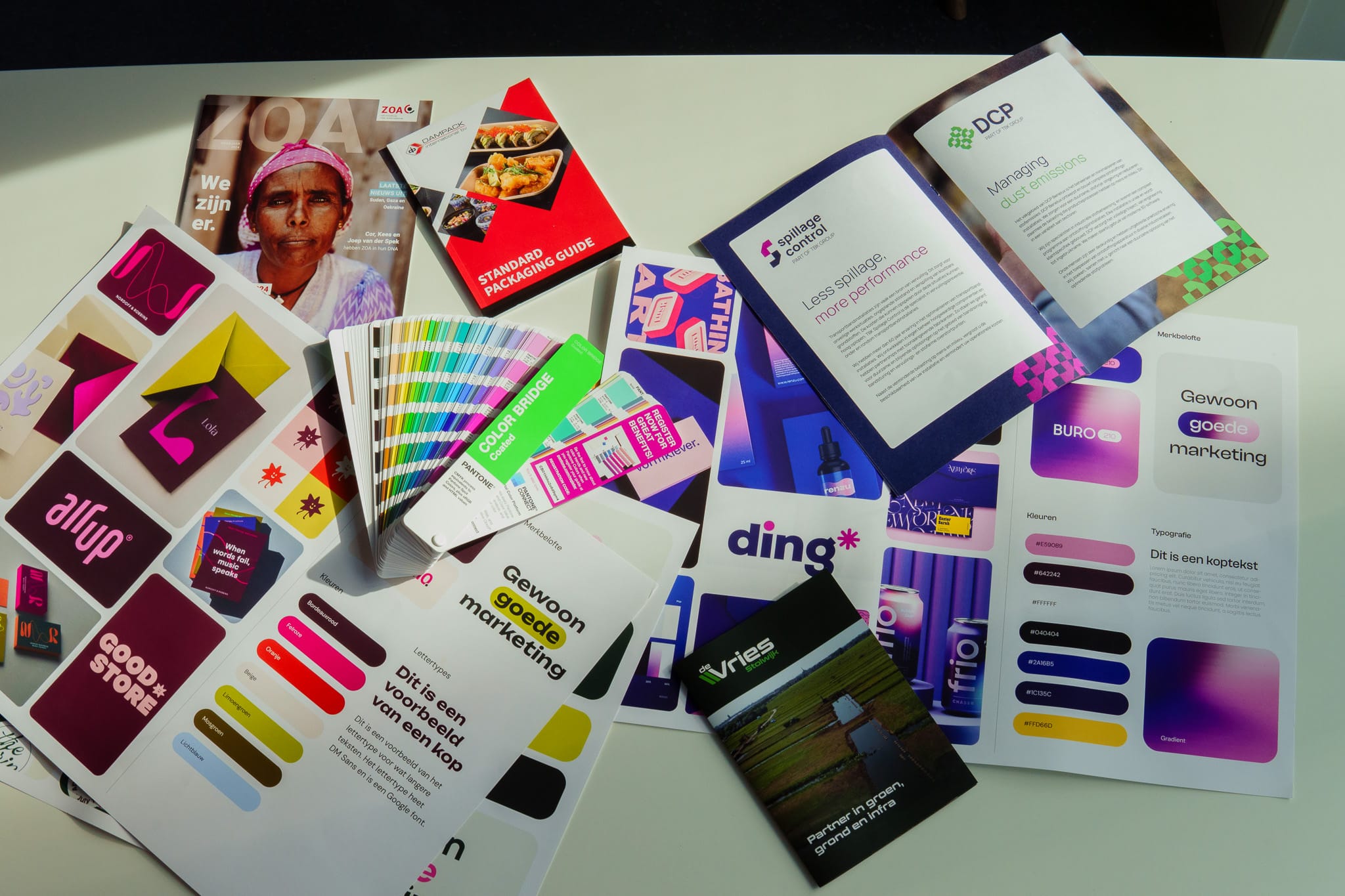 BURO210 Fullservice Marketingbureau Overzicht van marketingmaterialen, brochures, kleurkaarten en tijdschriften voor branding en bedrijfsidentiteit, ideaal voor grafisch ontwerpers en marketeers.