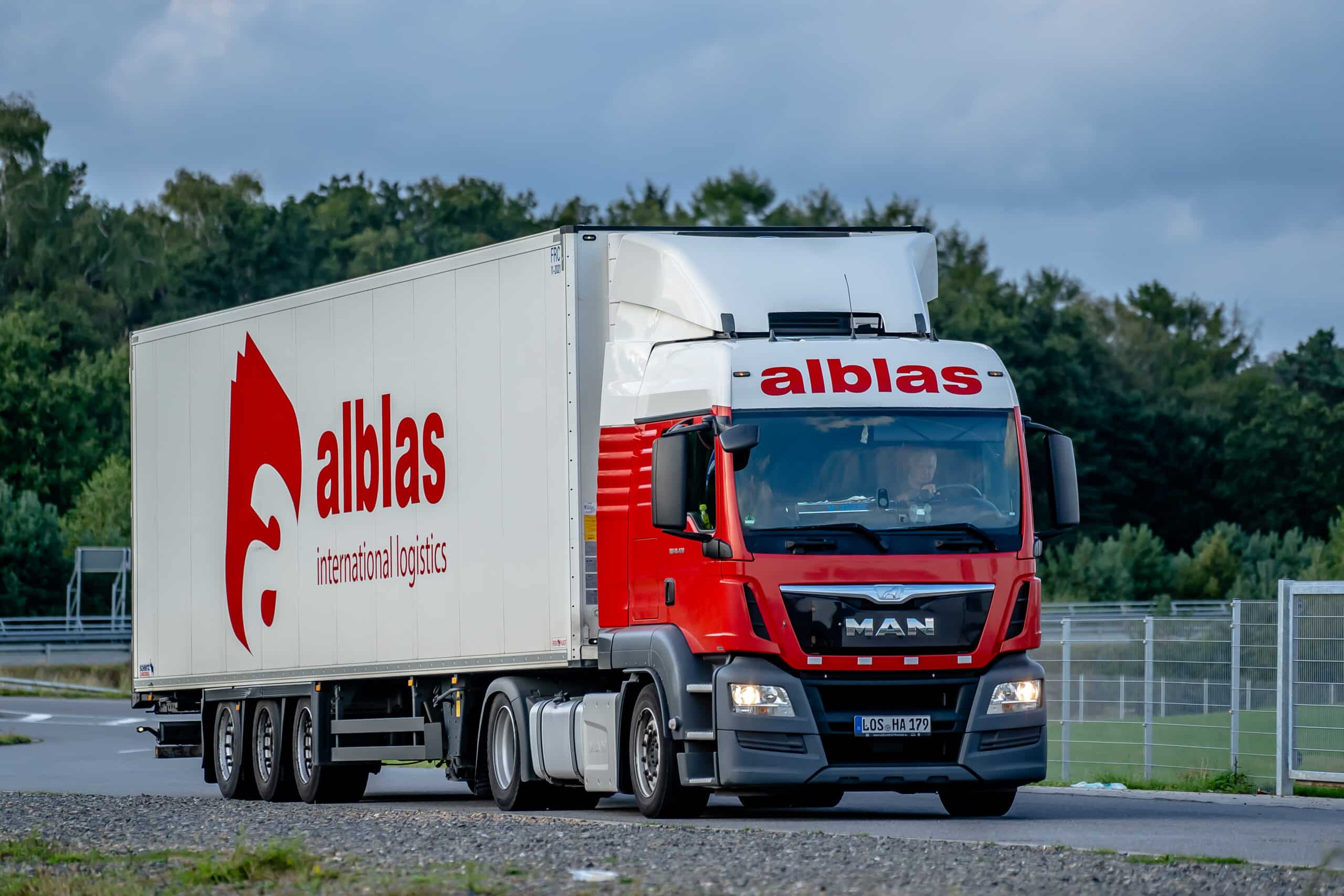 BURO210 Fullservice Marketingbureau Foto van een rode MAN-vrachtwagen van Alblas International Transport. Op de oplegger staat het rode Alblas-logo en 'international logistics'.