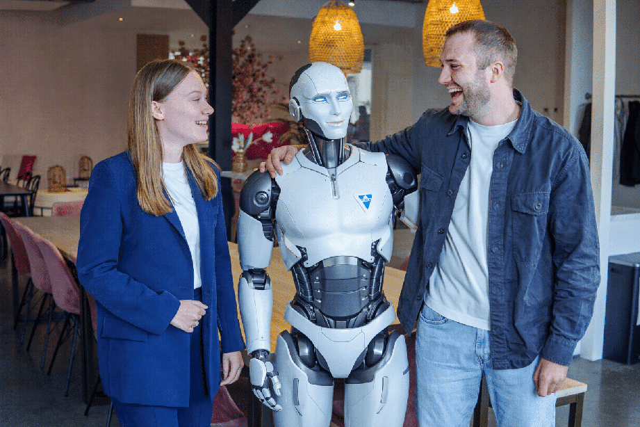 BURO210 Fullservice Marketingbureau Twee mensen lachen met een humanoïde robot in een moderne kantooromgeving. Geschikt voor buro210 innovatie.
