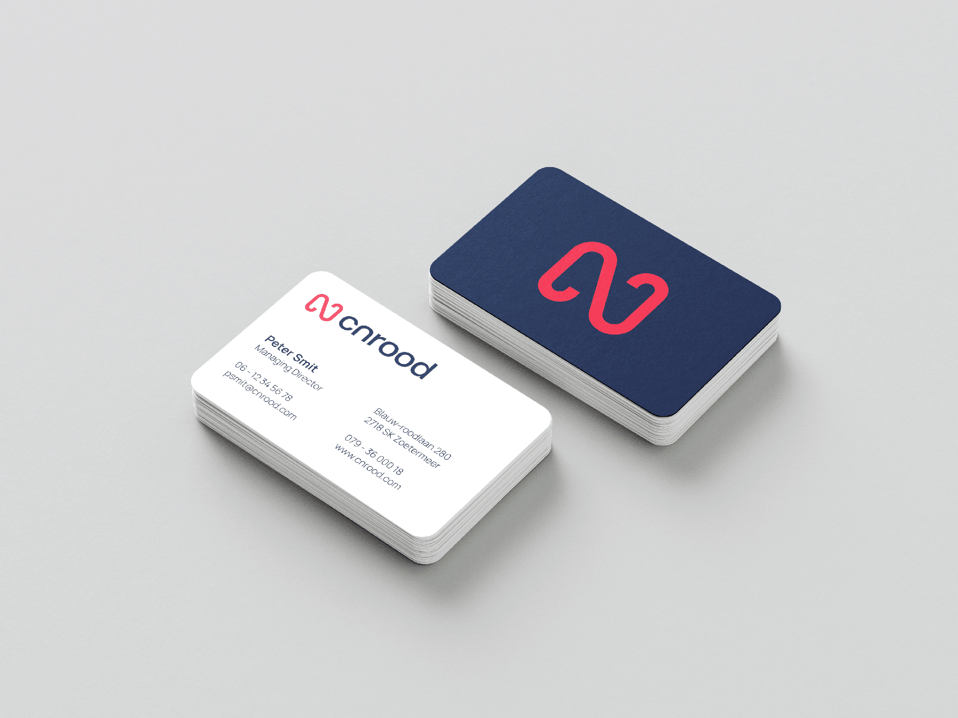 BURO210 Fullservice Marketingbureau Stapel visitekaartjes van CN Rood met een donkerblauw logo in rood en een witte zijde met contactgegevens op een grijze achtergrond.